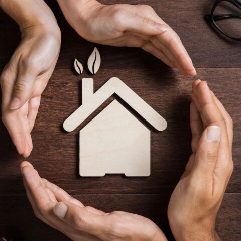 image of hands around wooden cut out of a house